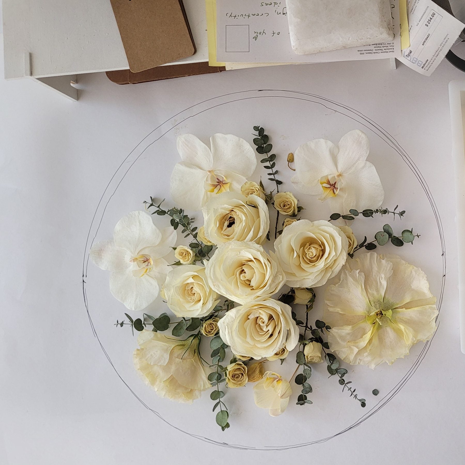 White roses and orchids laid out for a round glass preservation