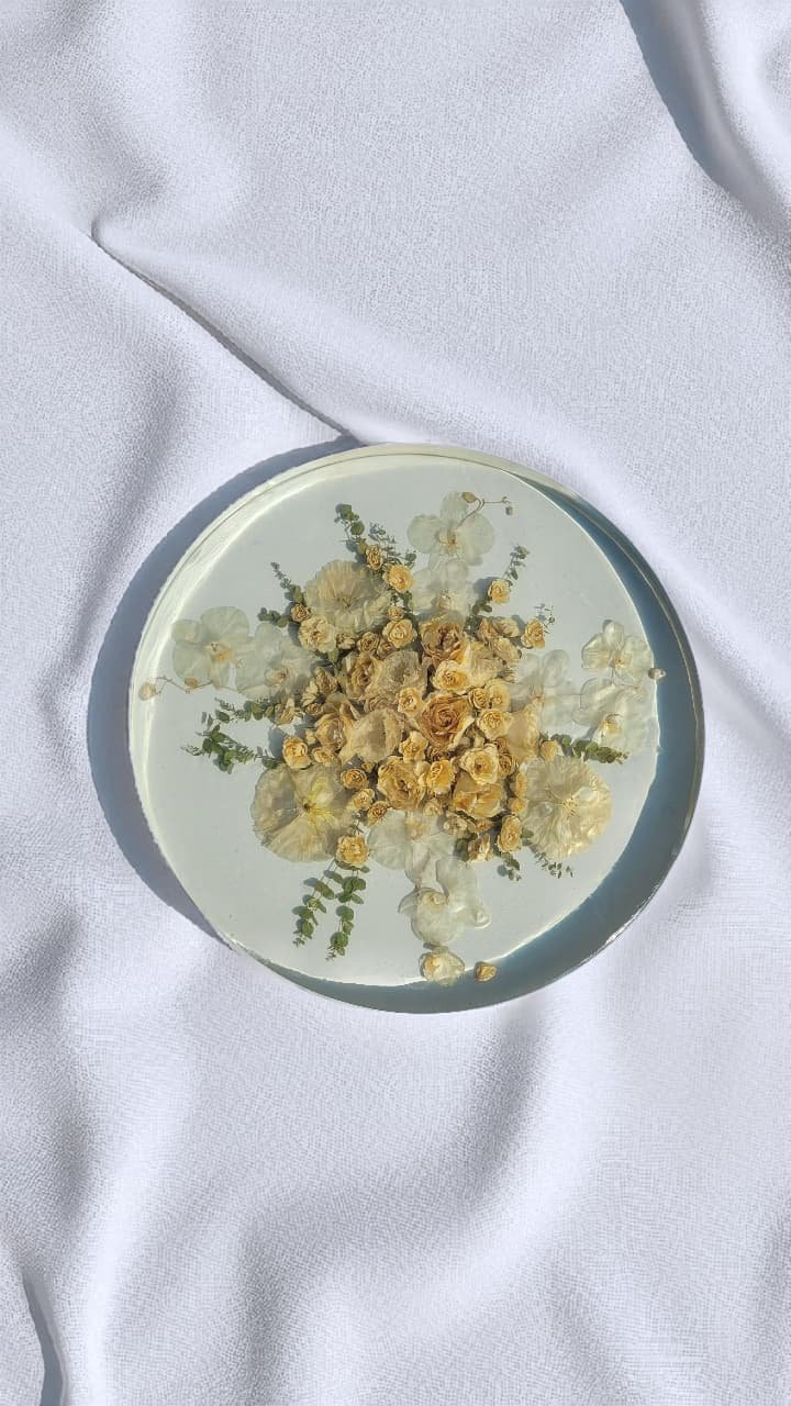 A preserved wedding bouquet set in a round resin table, on white cloth